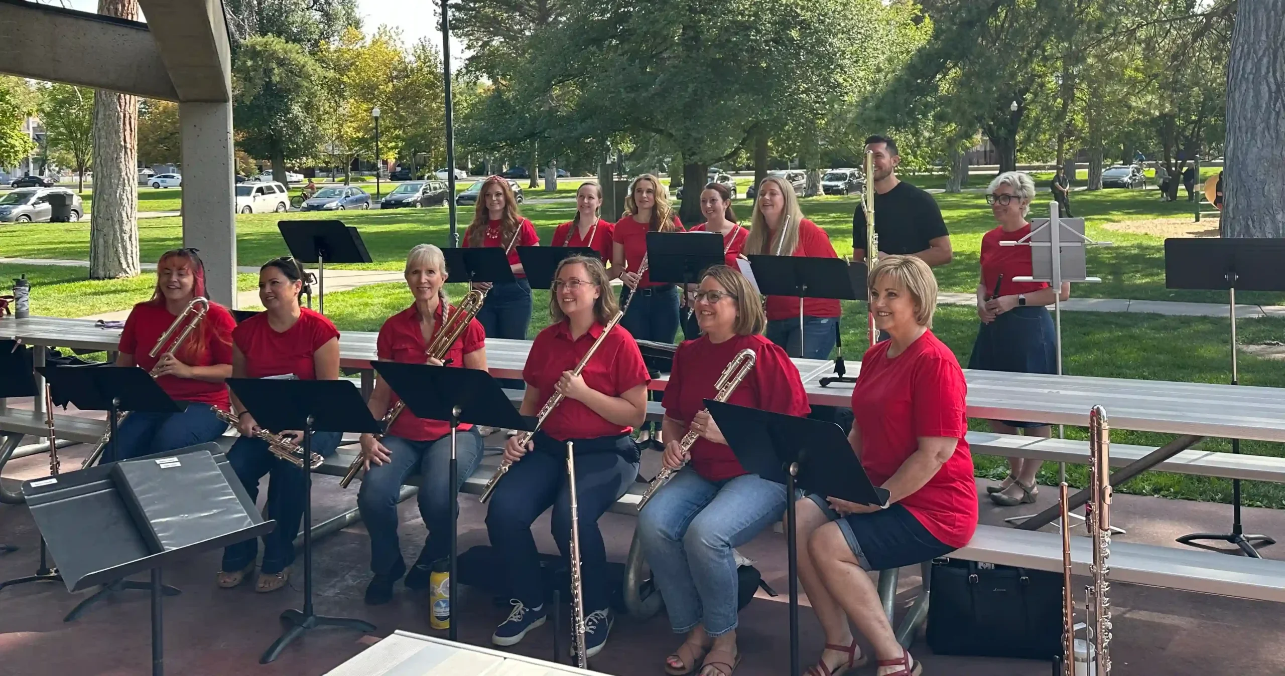 Members of the Utah Flute Association flute choir performing outdoors under a park pavilion at Glendale Park