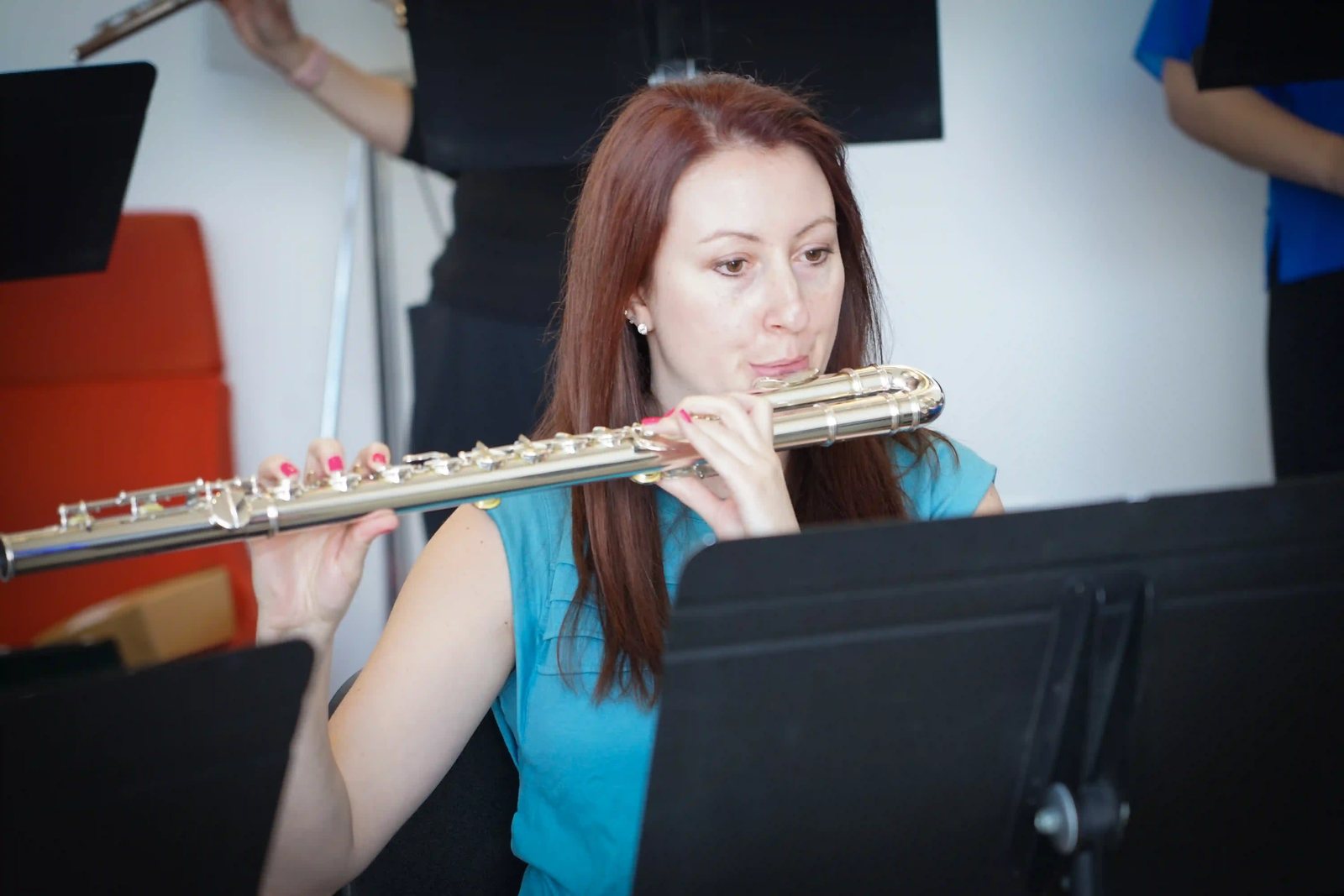 Katie Parker playing the flute while reading from a music stand during a Utah Flute Association rehearsal.