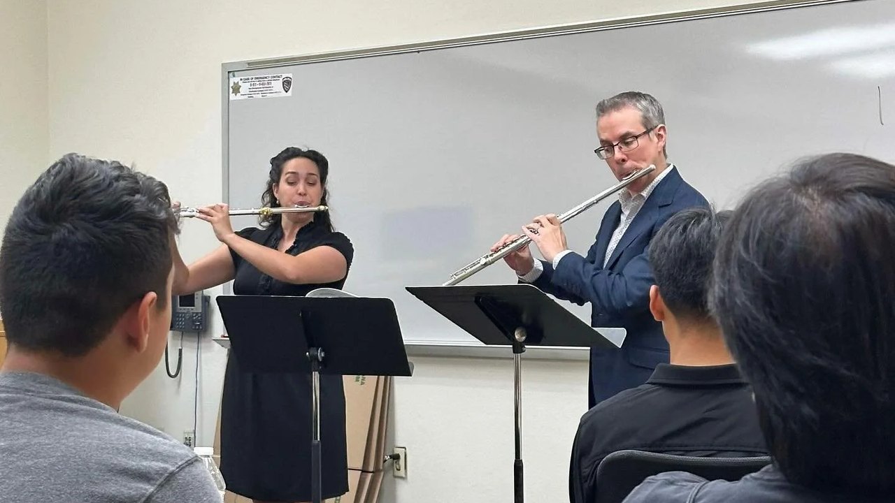 Two flutists performing together in front of a seated audience at a Utah Flute Association session