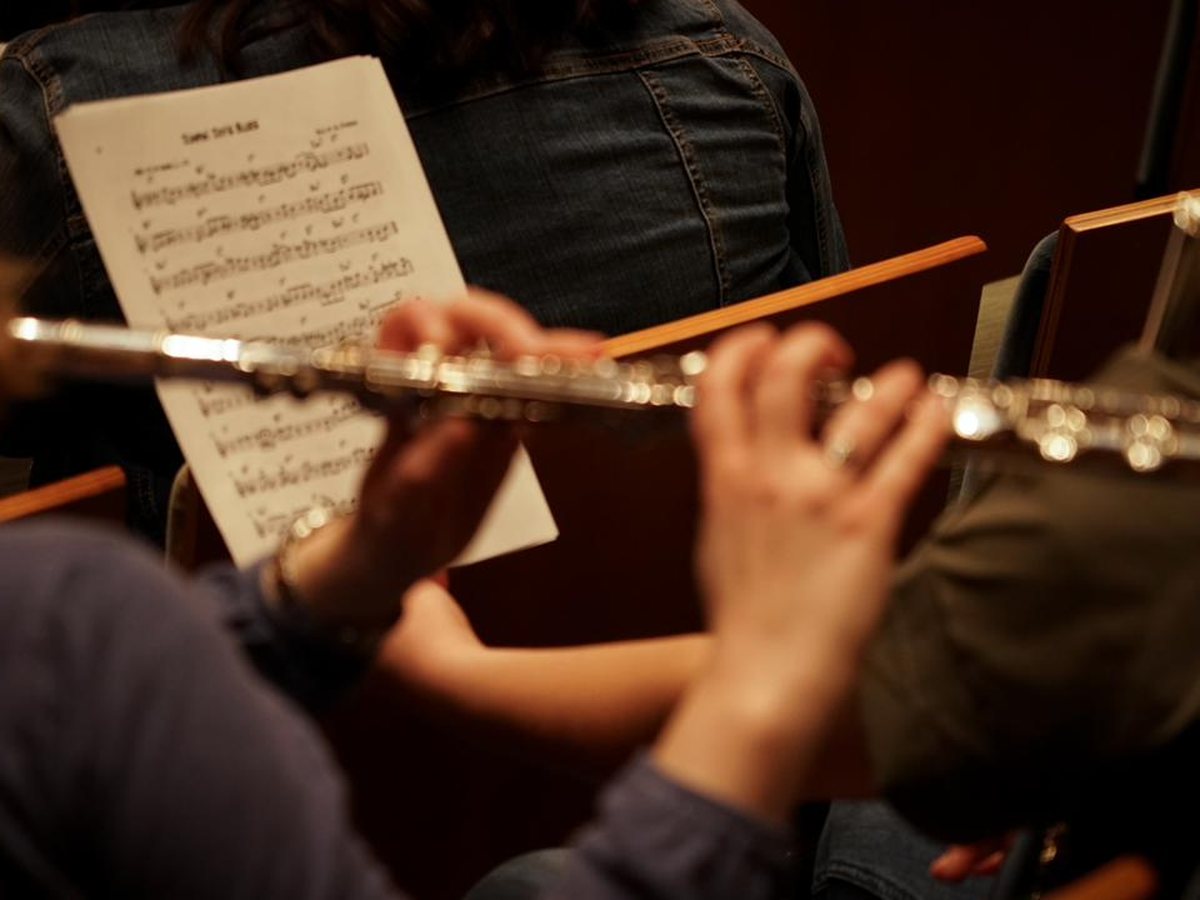 Sheet music on a stand with flutists playing from it during a Utah Flute Association rehearsal